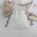 Gros plan de la pochette matelassée blanche en cœur avec cordons violets, sac de rangement. - 18*16cm / Blanc