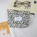 Vue détaillée de la trousse de maquillage en toile léopard avec étiquette et accessoires. - Pochette pour Rouge à Lèvres / Léopard Beige