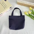 Detailed view of the solid color nylon mini tote bag showcasing fine stitching and fabric texture. - 21*6*27cm / Navy Blue