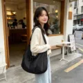 Vista dettagliata della borsa a tracolla nera casual, che mostra grande capacità e stile quotidiano. - Nero