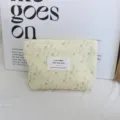Close-up detail of the yellow corduroy makeup pouch featuring charming floral print and textile label. - Cream Blue-Purple Floral Lipstick Bag
