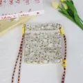 Close-up detail of the floral canvas crossbody bag with colorful straps and lace trim decoration. - Apricot with White Flower
