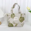 Detailed view of the vintage green floral jacquard lunch handbag, textured fabric and woven label. - Embossed Green Rose