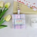 Detailopname van het ruitjes mini oortjes etui in college stijl met ophanglus en schattig stoffen label. - Roze-Blauw Geruit