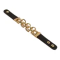 Detailaufnahme eines schwarzen Lederarmbands im Punk-Stil mit goldener Metallkette. - Punk-Stil Ketten-Design / Schwarz