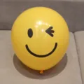 Yellow latex balloon close-up featuring printed black winking smiley face - Lemon Yellow Winking Face Style