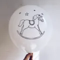 Close-up view of a white latex party balloon featuring a black rocking horse print - 白色印木马款