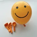 Bright orange thickened latex balloon featuring a classic black smiley face print for events - Lemon Yellow Smiley