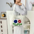 Close-up detail of white quilted tote bag featuring colorful embroidered tulip flowers. - Tulip Floral Style (Polyester) / White