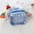 Vista dettagliata della borsa cosmetica a quadri blu e bianchi con volant e chiusura lampo. - Quadri Blu Scuro