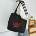 Vista detallada del bolso tote de lona negro con bordado de cerezas y estilo al hombro. - Look Cereza Negro