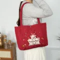 Gedetailleerd overzicht van de rode gewatteerde tote tas met schattig varkensborduurwerk. - Wijnrood (Drie Kleine Biggetjes)