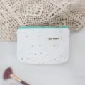White canvas pouch featuring silver star sequins, detailed view of cosmetic makeup bag. - White