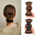 Details view of brown bow hair bun extension with black claw clip for easy styling. - Tan