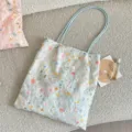 Detailansicht einer hellblauen, blumenbestickten Segeltuchtasche mit schmalen Trägern. - Blau