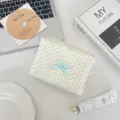 Vue détaillée de la trousse de maquillage en tissu à pois avec un nœud papillon. - Beige