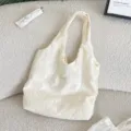 Detail shot of a cream floral embroidered canvas vest bag on a soft cozy textured fleece background. - Vest Bag