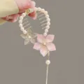 Primer plano de un elegante pasador de flores con perlas y borla larga - Pink bead flower hairpin