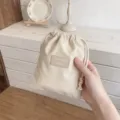 Gedetailleerd overzicht van effen trekkoordtas, draagbare opbergtas voor cosmetica en koptelefoon. - S / Beige