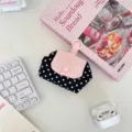 Detailansicht der niedlichen schwarz-weißen Pünktchen-Tasche mit rosa Klappe und Aufhängeöse. - Schwarze Punkte