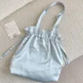 Detalle de un bolso de hombro de satén con lunares azul claro y delicado bordado floral. - Azul claro