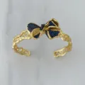 Vergoldeter offener Armreif mit filigraner Schleife und blauem Zirkonia-Besatz im Retro-Look. - Blauer Armreif