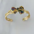 Retro goldfarbenes Armband mit offener Manschette und funkelnder mehrfarbiger Zirkon-Schleife. - Armreif-Bunt