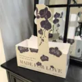 Beige paper flower carrier box with purple orchid print and elegant romantic text design. - Purple