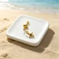Macro view of gold star charms on a white beach plate showing 1.3cm dimensions - Smooth Four-Pointed Star