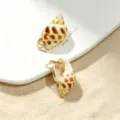 Close-up of ocean style seashell charms with dimensions 3x1.5cm on beach sand. - Natural Spotted Conch Pendant
