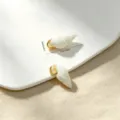 Detailed size view of white conch shell charm with gold ring on sunny sand background - Natural White Small Conch