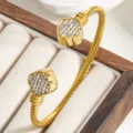 Gold-plated twisted cable cuff bracelet with paved crystal clover ends, minimalist luxury style. - Gold