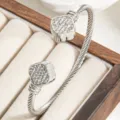 Close-up detail of the twisted cable wire cuff bracelet featuring sparkling rhinestone clover ends. - Steel