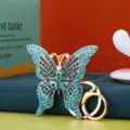 Dettaglio di un portachiavi a farfalla di lusso con strass blu e anello dorato. - Vestibilità regolare / Blu viola
