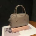 Gros plan d'un sac à main Boston en cuir vintage gris-brun posé sur un livre rétro. - Gris Écureuil
