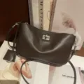 Detailed view of dark brown leather underarm shoulder bag with metal twist lock closure. - 23*5*13cm / Coffee