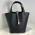 Detailed view of the black leather bucket handbag with metal lock, elegant and spacious. - Black with Gold Buckle
