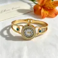 Detaillierte Ansicht einer goldenen Armreif-Uhr mit glitzernden Strasssteinen und Türkis - Hohlmuster-Stil mit Türkis-Akzent (YF-26SZ00319)
