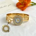 Nahaufnahme einer goldenen Armreif-Uhr mit Strasssteinen und römischen Ziffern - Doppelschichtiger Stil mit römischen Ziffern (JYD-25SZ00325)