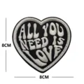 Heart-shaped embroidered patch with All You Need Is Love text, ideal for clothing and bags. - Black and White