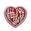 Close-up of red heart embroidered patch with white text All You Need Is Love design. - Red and White