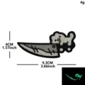 Primer plano detallado del parche táctico bordado de gato lindo con diseño luminoso. - Gato blanco luminoso sosteniendo un cuchillo