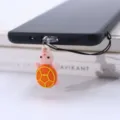 Nahaufnahme eines niedlichen rosa-orangen Schildkröten-Handyanhängers an einem Smartphone. - Type-C / Orangefarbene Schildkröte