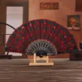 Detalle de un abanico español con lentejuelas rojas y bordados sobre tela negra. - Abanico bordado con lentejuelas rojas