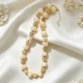 Primer plano del elegante collar de cuentas acrílicas con espaciadores metálicos dorados. - Blanco