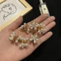 Primo piano di eleganti mollette per capelli a fiore di perla - Mini clip per capelli a fiore a cinque petali con perle dorate (set di 5)