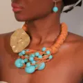 Close-up of handmade turquoise beaded necklace with gold alloy pendant on model - Necklace And Earrings