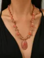 Close-up of dopamine style resin beaded necklace with large peach teardrop pendant - Pink