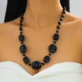 Chunky black resin beaded necklace with gold spacer beads on model - Black