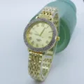Goldene Strass-Quartzuhr für Damen im Detail mit römischen Ziffern und funkelnder Lünette. - Gold Gold